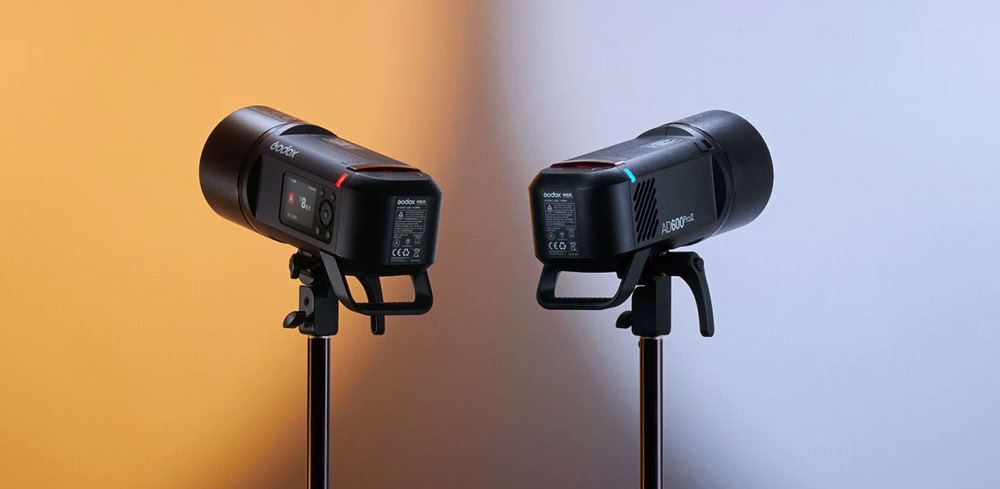 Два акумуляторні спалахи Godox AD600Pro II встановлені на чорних студійних стійках, освітлені теплим жовтим та холодним синім світлом з різних боків; на корпусі читається маркування AD600ProII